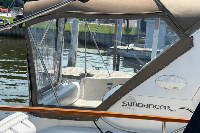 Slide: The Image of 1996 Sea Ray Sundancer 330 boat docked, featuring clear enclosure and branding. - 11