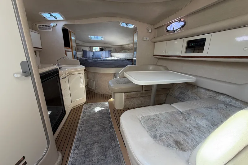 Slide: The Image of Interior of a 1996 Sea Ray Sundancer 330 yacht, featuring a cozy dining and sleeping area. - 26