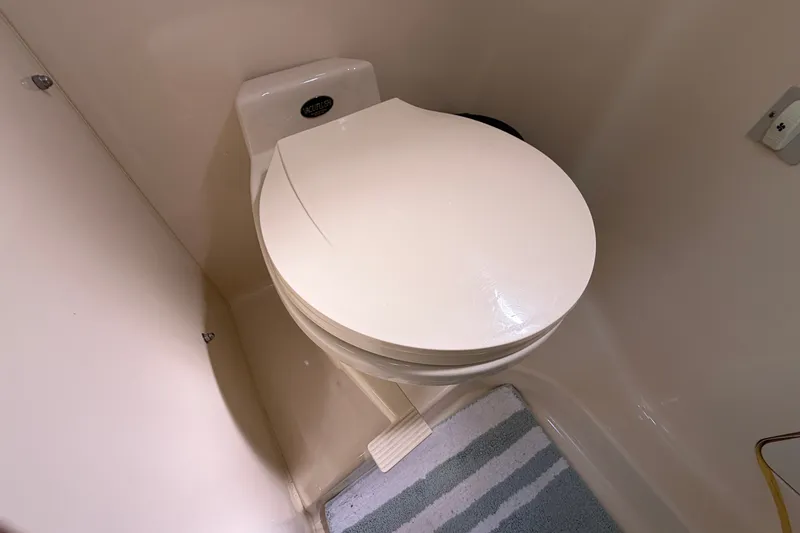 Slide: The Image of 1996 Sea Ray Sundancer 330 bathroom with a compact marine toilet and striped rug. - 47