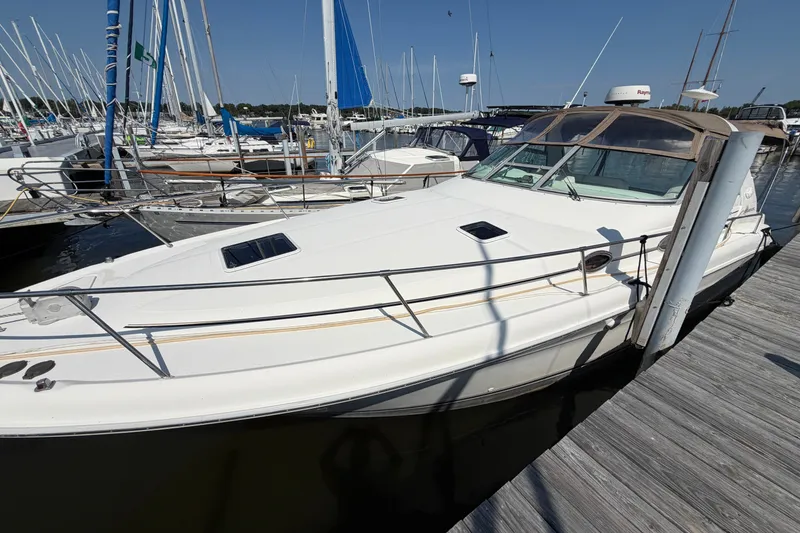 Slide: The Image of 1996 Sea Ray Sundancer 330 docked at marina, surrounded by sailboats under clear blue sky. - 4