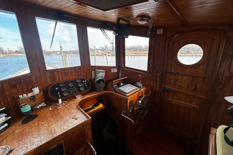 Slide: The Image of 1983 Lord Nelson Victory Tug/Trawler interior with wooden helm, gauges, and river view. - 19