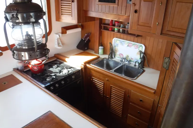 Slide: The Image of Cozy 1983 Lord Nelson Victory Tug kitchen with stove, sink, and wooden cabinetry. - 45