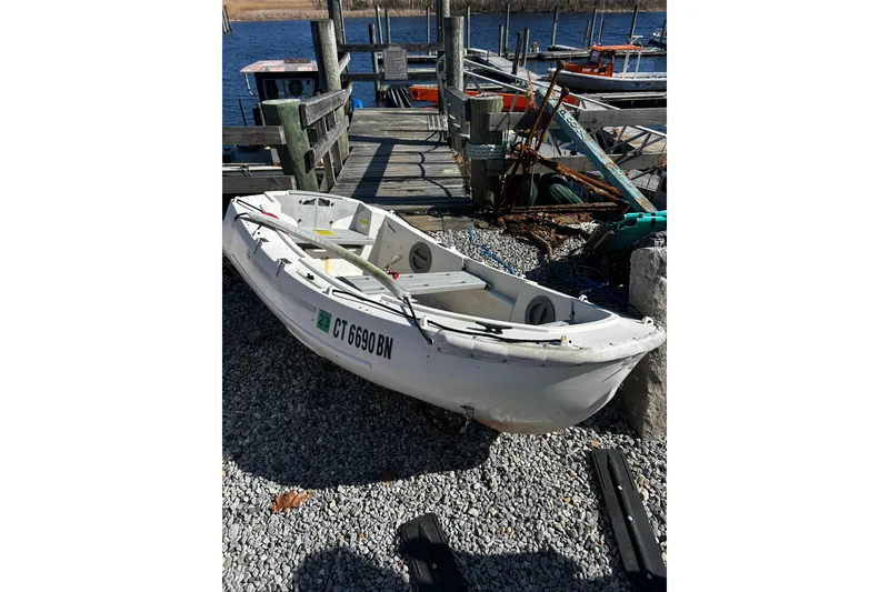 Slide: The Image of Small white boat docked on gravel near a pier, with registration number CT 6690 BN. - 56
