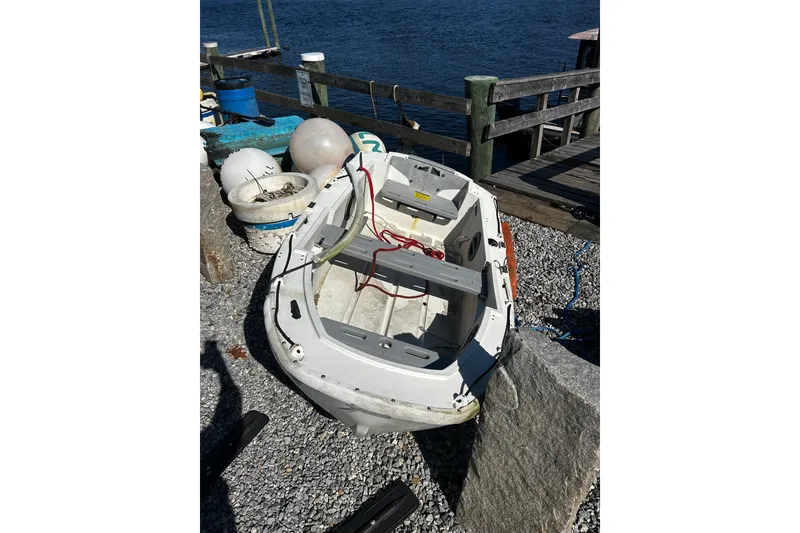 Slide: The Image of Small boat docked by the shore, near a wooden pier and nautical equipment. - 57
