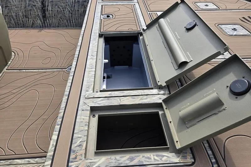 Slide: The Image of 2025 Tracker Grizzly 2072 CC boat storage compartments open on deck. - 16
