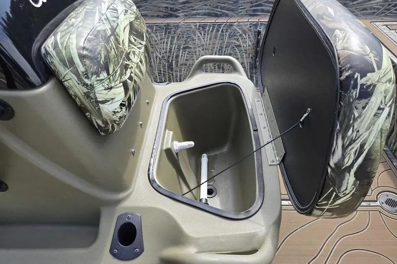 Slide: The Image of 2025 Tracker Grizzly 2072 CC boat storage compartment with open lid and camouflage seating. - 15