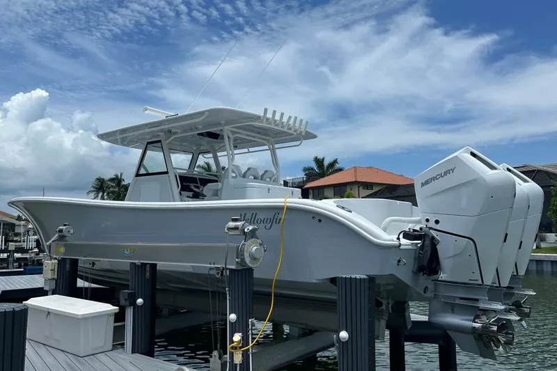 Slide: The Image of 2026 Yellowfin 39 Offshore boat with Mercury engines on a lift, under a blue sky. - 5