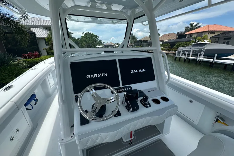 Slide: The Image of 2026 Yellowfin 39 Offshore boat cockpit with Garmin navigation system, docked by waterfront homes. - 39