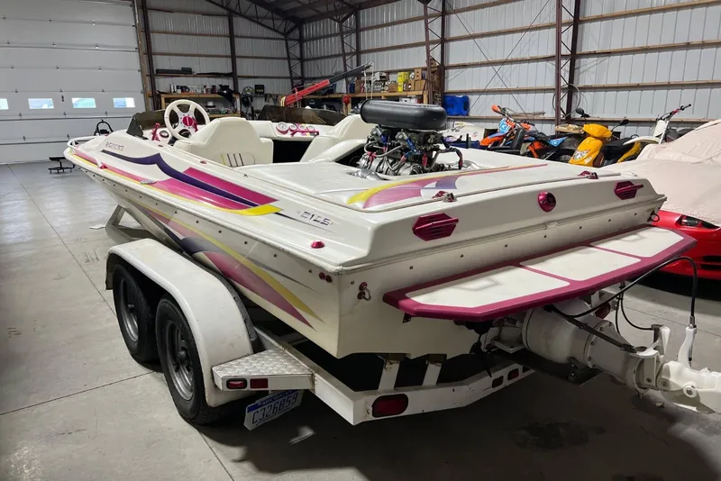 Slide: The Image of 1999 Shockwave 21LS speedboat with vibrant graphics, parked in a spacious garage. - 13