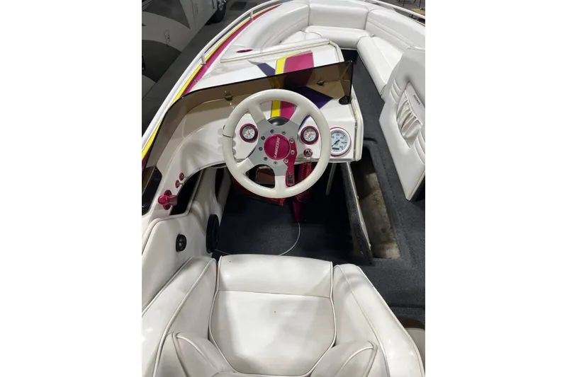 Slide: The Image of Interior of a 1999 Shockwave 21LS boat with white seating and colorful dashboard. - 7