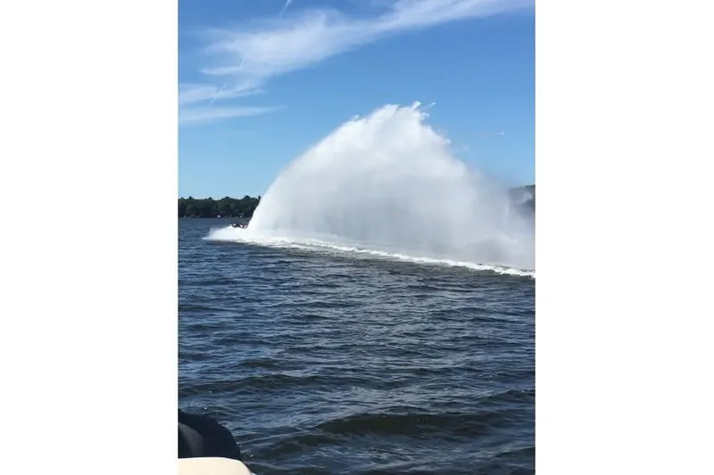 Slide: The Image of High-speed Shockwave 21LS boat creating a large water spray on a sunny day. - 21