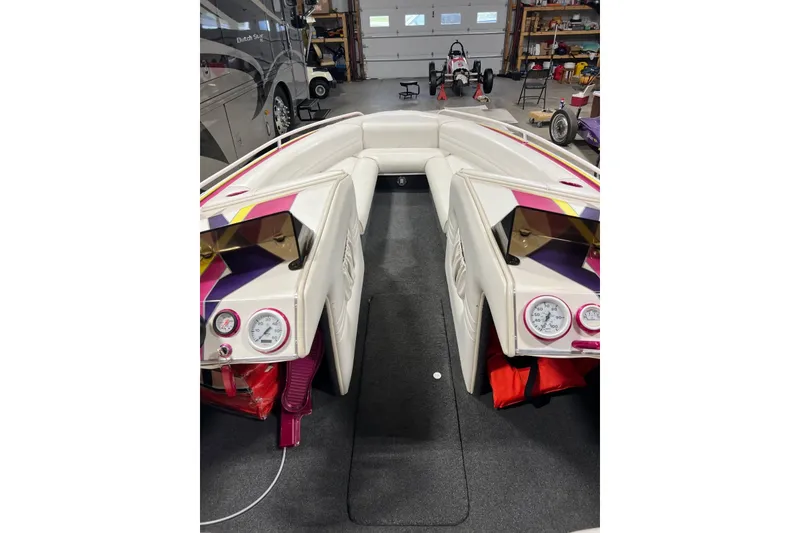 Slide: The Image of 1999 Shockwave 21LS boat interior with colorful dashboard and seating in a garage setting. - 5