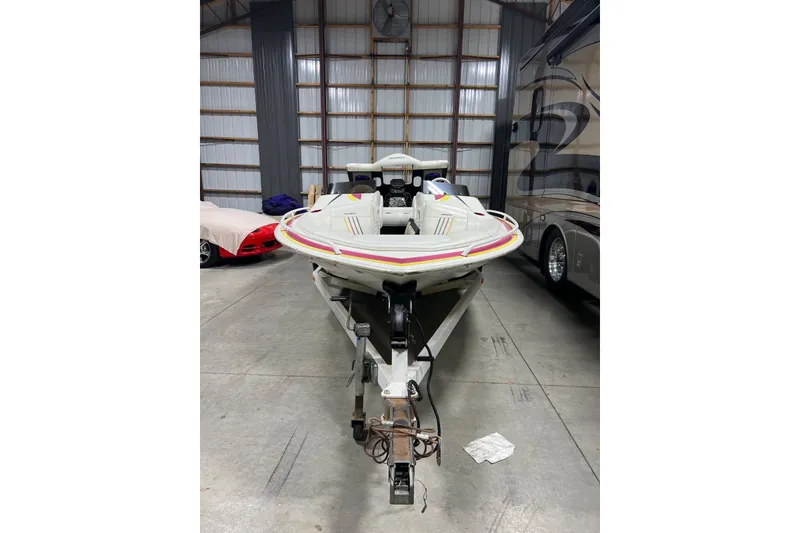 Slide: The Image of 1999 Shockwave 21LS boat on trailer in a garage, surrounded by vehicles. - 20