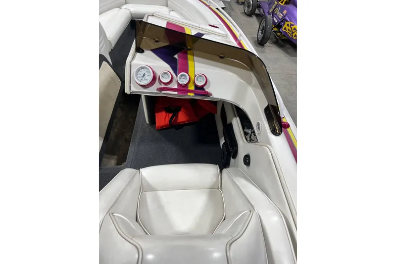 Slide: The Image of 1999 Shockwave 21LS boat interior with white seating, dashboard gauges, and colorful accents. - 10