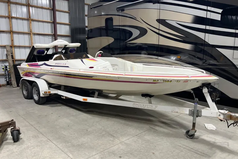 Slide: The Image of 1999 Shockwave 21LS boat on trailer in a garage setting. - 2