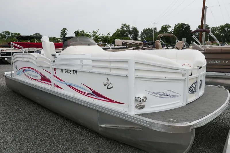 The Image of 2011 JC 23 SunLounger TT pontoon boat with white and red design, parked on gravel. - 0