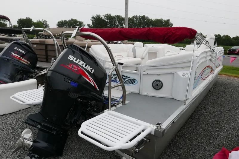 Slide: The Image of 2011 JC 23 SunLounger TT pontoon boat with Suzuki outboard motor, parked on gravel. - 2