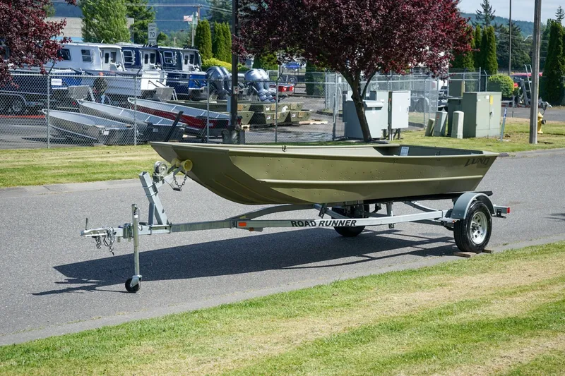 Slide: The Image of 2025 Lund 1648M boat on trailer, parked outdoors near a fence and trees. - 7