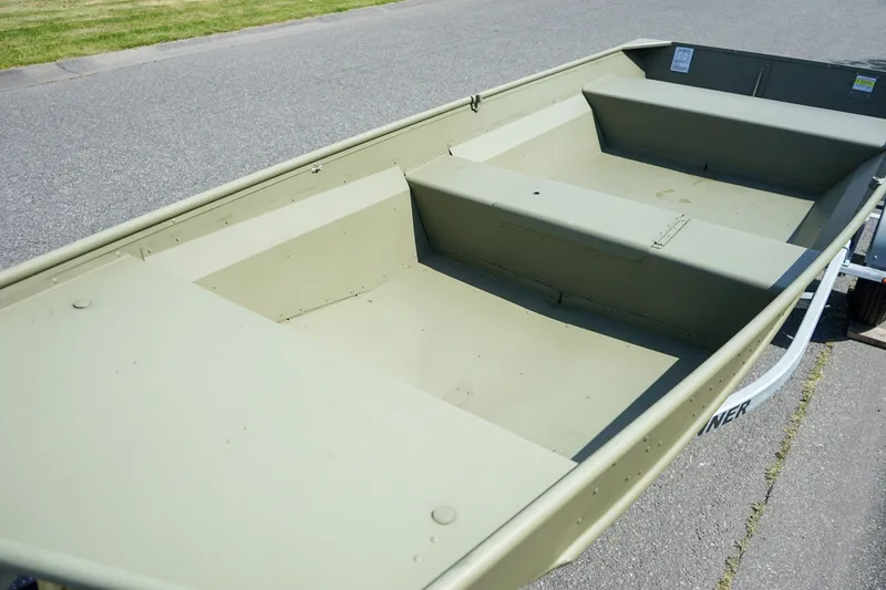 Slide: The Image of 2025 Lund 1648M boat on trailer, parked on pavement, showcasing interior seating and design. - 6