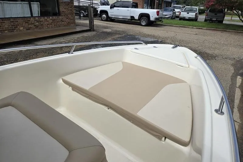 Slide: The Image of 2025 Scout 175 Sportfish boat interior with beige seating, parked outdoors. - 12