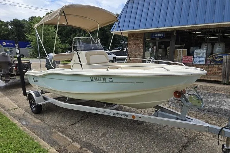 Slide: The Image of 2025 Scout 175 Sportfish boat on trailer, parked outside a marine store. - 2
