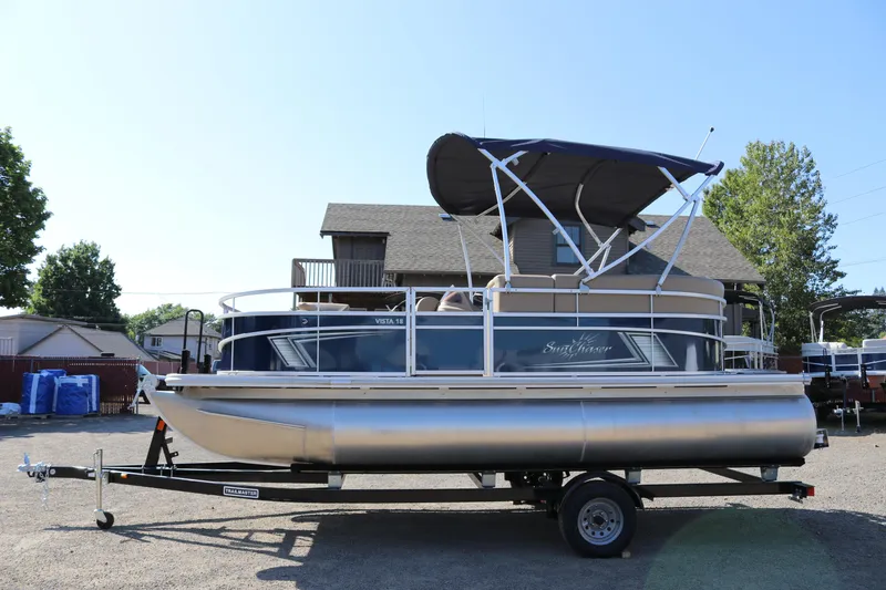 Slide: The Image of 2025 Sun Chaser Vista Fish 18 pontoon boat on trailer, parked outdoors. - 1