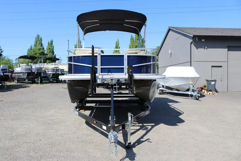 Slide: The Image of 2025 Sun Chaser Vista Fish 18 pontoon boat on trailer, parked outdoors. - 2