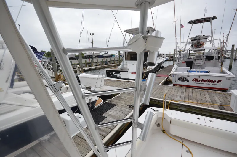 Slide: The Image of 2004 Luhrs 320 Open boat docked at marina, featuring fishing rod holders and nearby vessels. - 13