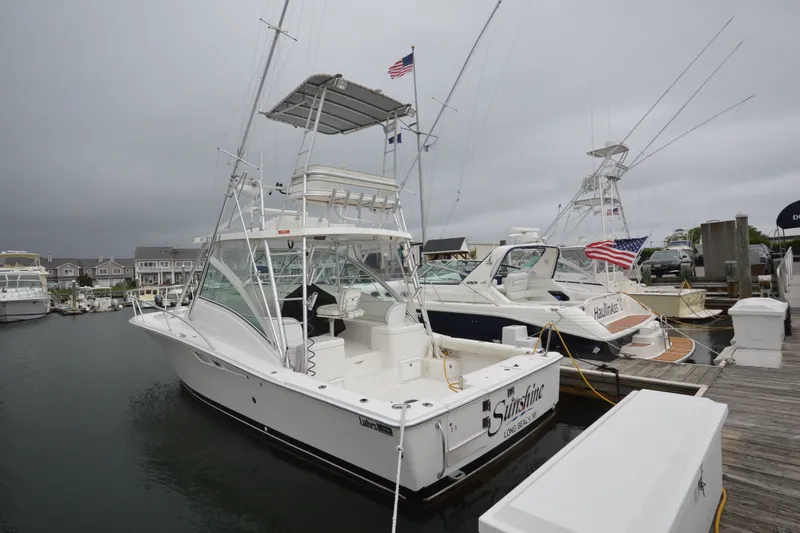 The Image of 2004 Luhrs 320 Open boat docked at marina, featuring fishing equipment and American flag. - 3