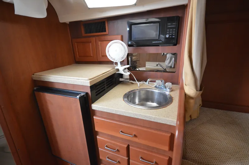 Slide: The Image of 2004 Luhrs 320 Open boat interior with kitchenette, featuring sink, microwave, and compact fridge. - 20