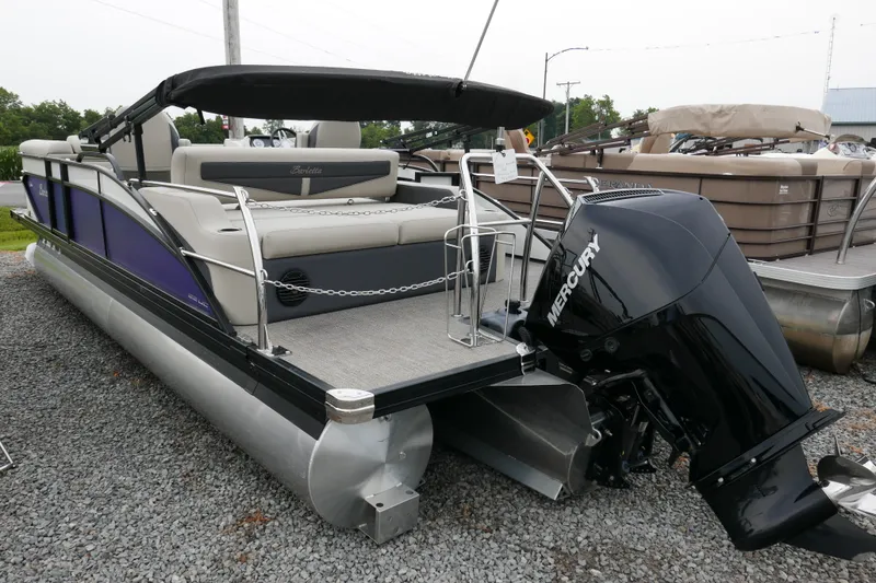Slide: The Image of 2023 Barletta Cabrio C22UC pontoon boat with Mercury engine, displayed on gravel lot. - 2