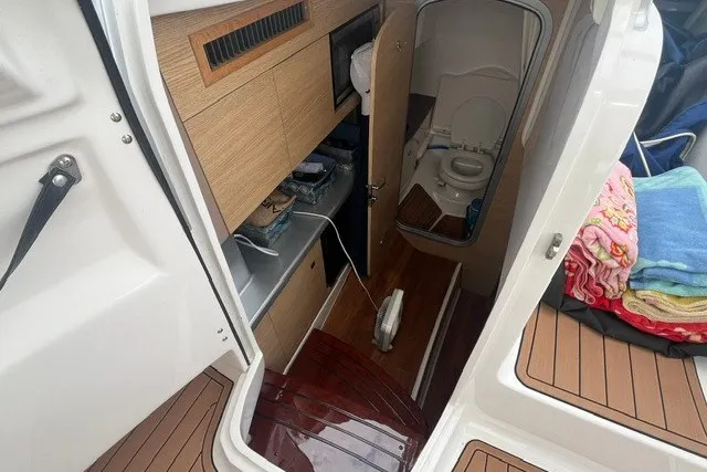Slide: The Image of Interior view of 2013 Chaparral 327 SSX boat, featuring a compact bathroom and wooden flooring. - 29