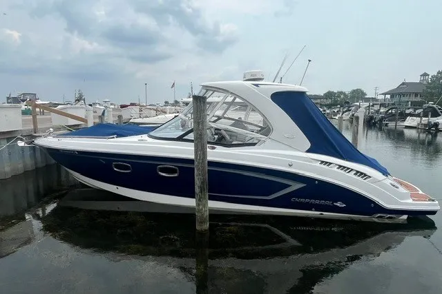 Slide: The Image of 2013 Chaparral 327 SSX boat docked at a marina, featuring a sleek blue and white design. - 2