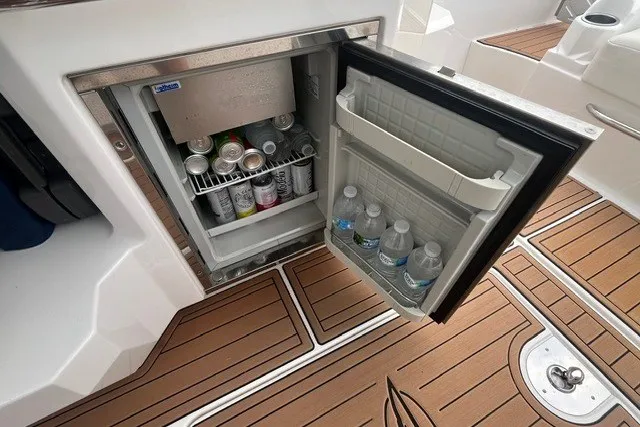Slide: The Image of Mini fridge stocked with drinks on 2013 Chaparral 327 SSX boat, featuring teak flooring. - 28