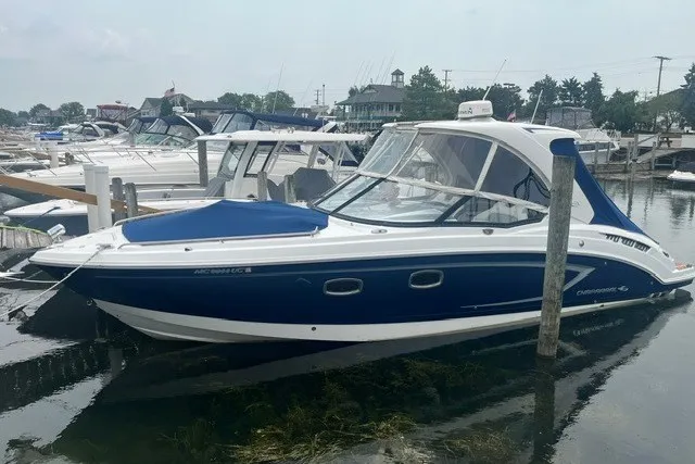 The Image of 2013 Chaparral 327 SSX boat docked in a marina, featuring a sleek blue and white design. - 0