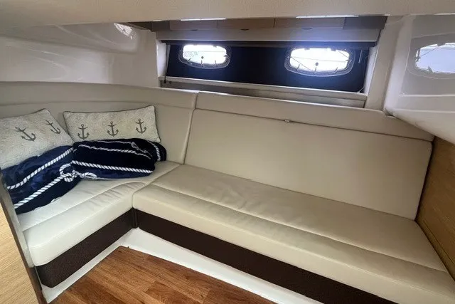 Slide: The Image of 2013 Chaparral 327 SSX cabin interior with beige seating and nautical-themed cushions. - 31