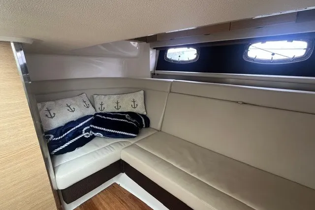 Slide: The Image of 2013 Chaparral 327 SSX cabin interior with beige seating and nautical-themed pillows. - 32