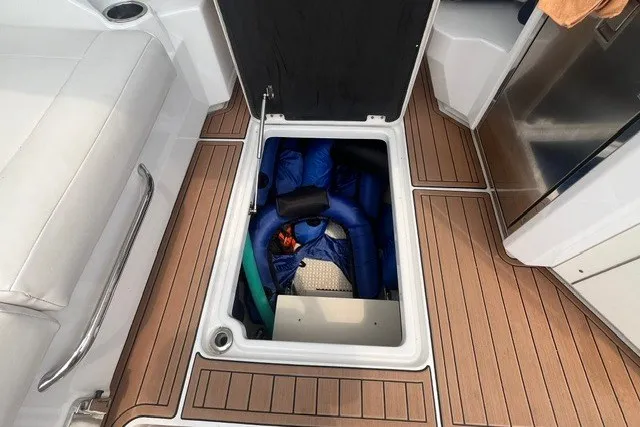 Slide: The Image of 2013 Chaparral 327 SSX boat storage compartment with blue and green equipment inside. - 13