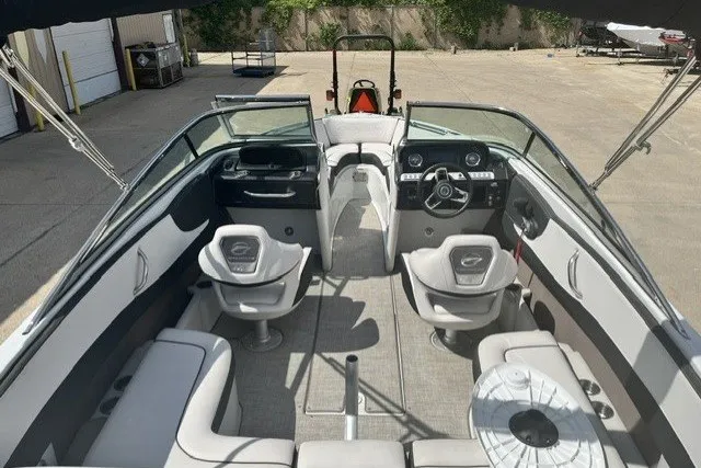 Slide: The Image of 2022 Crownline 240 SS boat interior with seating and steering wheel, parked outdoors. - 4