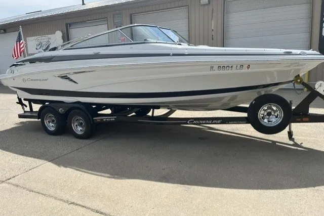 Slide: The Image of 2022 Crownline 240 SS boat on trailer, parked outdoors near garage. - 3