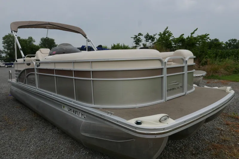 The Image of 2014 Bennington 2250GSR pontoon boat on gravel, featuring beige and silver design. - 0