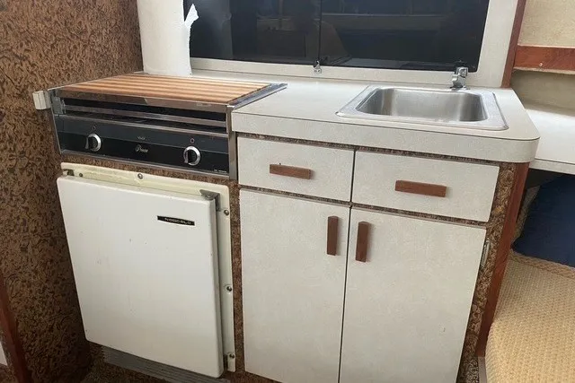 Slide: The Image of 1975 Slickcraft 28 EXPRESS boat kitchenette with stove, sink, and storage cabinets. - 13