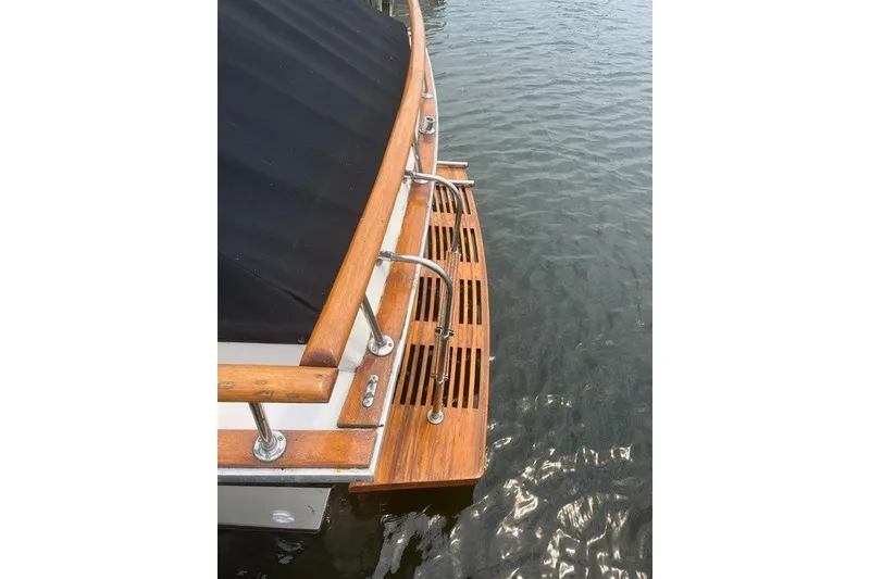 Slide: The Image of 1975 Slickcraft 28 EXPRESS boat with wooden deck and railing on water. - 4