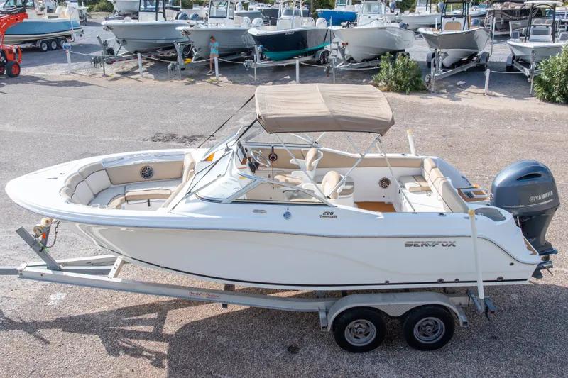 Slide: The Image of 2016 Sea Fox 226 Traveler boat on trailer, parked in marina with other boats. - 3