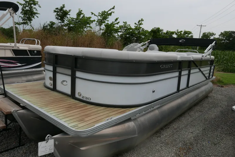The Image of 2018 Crest II pontoon boat with sleek design, parked on gravel near greenery. - 0