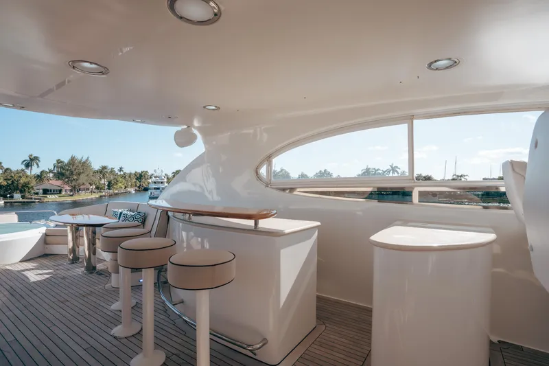 Slide: The Image of Luxurious 2004 Lazzara 106 yacht deck with bar stools and scenic waterfront view. - 17
