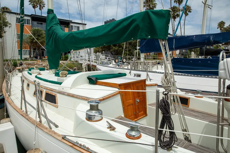 Slide: The Image of 1979 C&L Marine 36 sailboat docked, featuring green sail cover and wooden cabin door. - 16