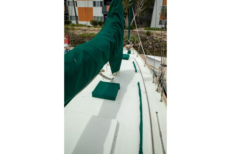 Slide: The Image of 1979 C&L Marine 36 sailboat deck with green covers, docked near buildings. - 17