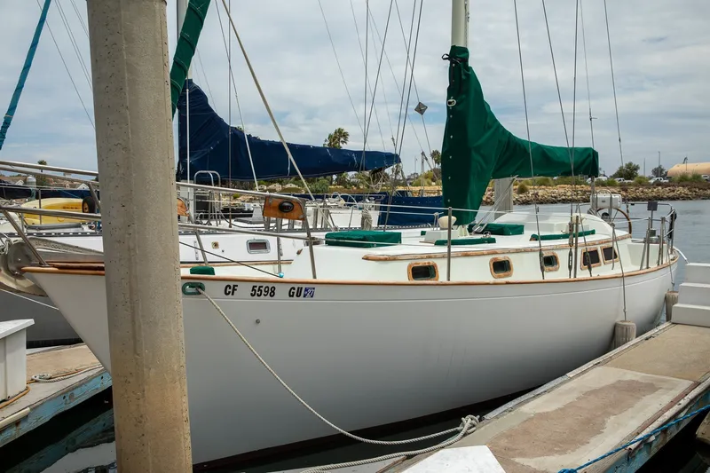 The Image of 1979 C&L Marine 36 sailboat docked at a marina with green sail covers. - 0