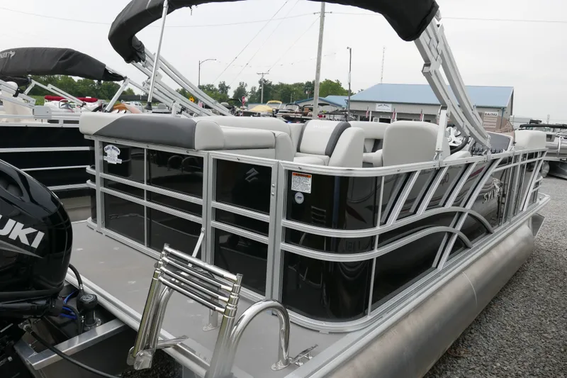 Slide: The Image of 2025 Sylvan Mirage 820 Cruise pontoon boat with Suzuki outboard motor, docked on gravel. - 2
